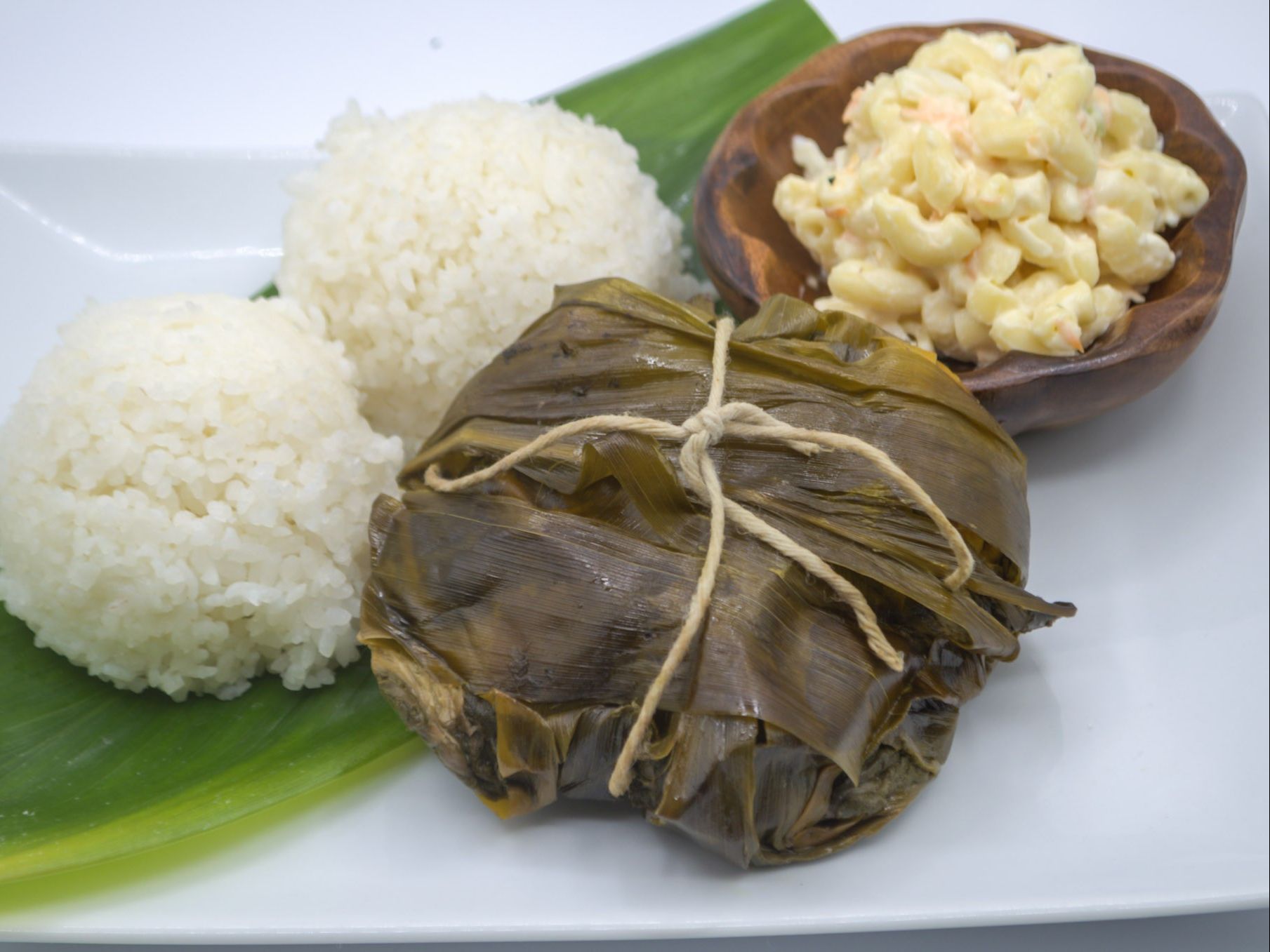 #1 Lau Lau & Macaroni Salad from Yama's Fish Market — Our signature lau lau — chicken, pork, and fresh luʻau leaf hand-wrapped in ti leaves and slow-cooked for over five hours until perfectly tender. Served with creamy mac salad and white rice.
